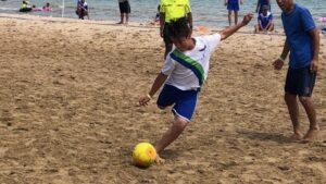 young male sand soccer player gets ready to kick the ball